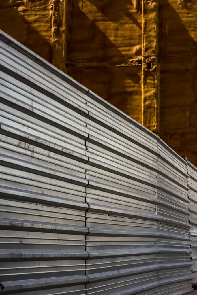 pexels-photo-31148721-31148721 Textured metal sheets against an industrial wall, highlighted by sunlight.